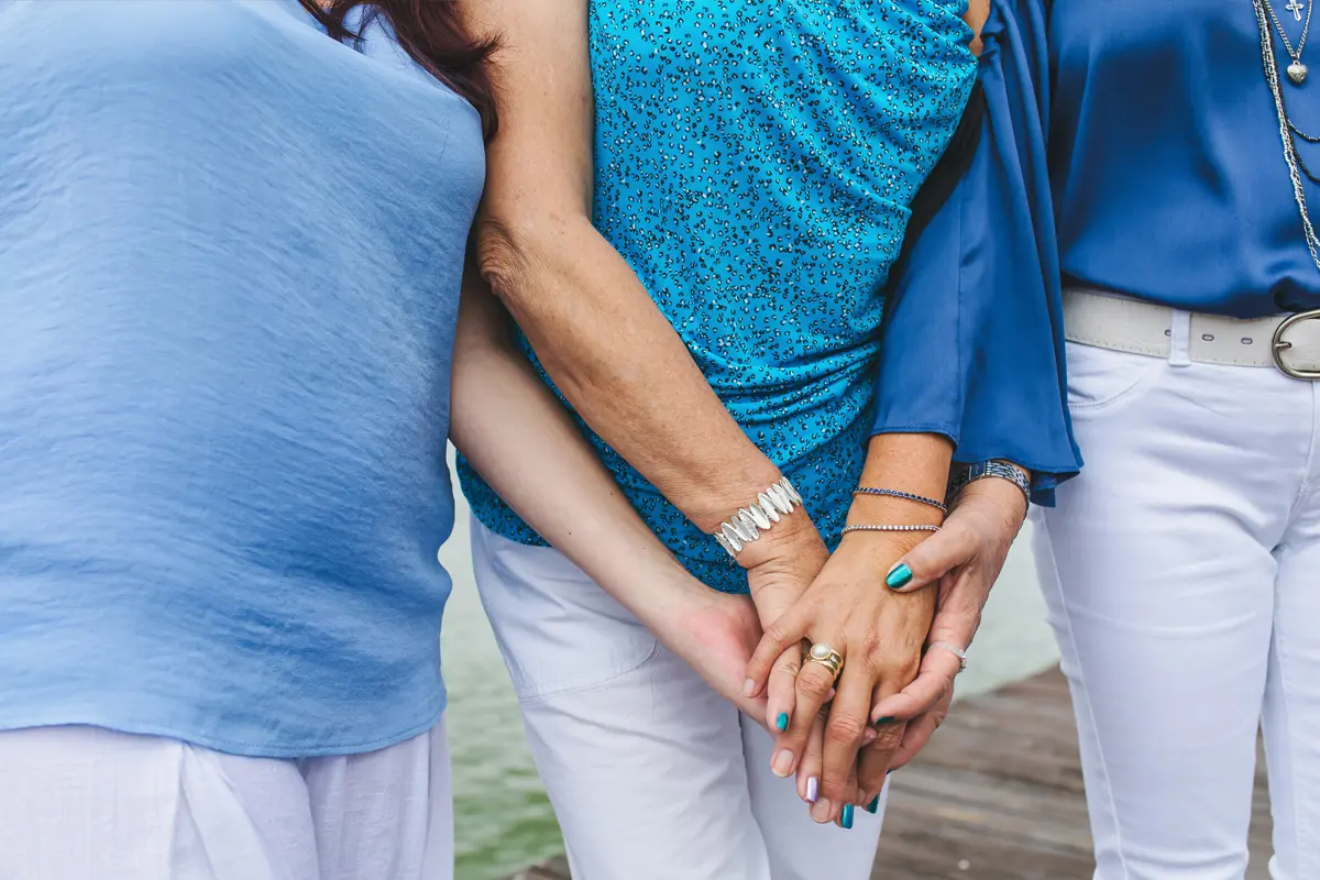 Tre persone che si tengono per mano all'aperto in riva al mare